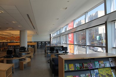 Book shelves and tables next to windows. Light Shelf - Bronx Library, New York