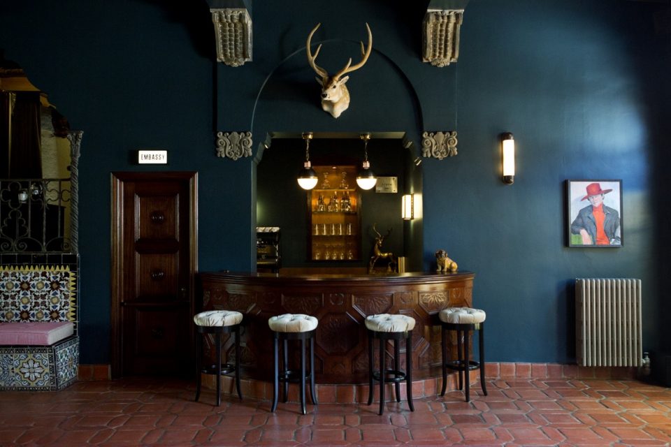 Dark blue walls with a wooden bar and barstool seating