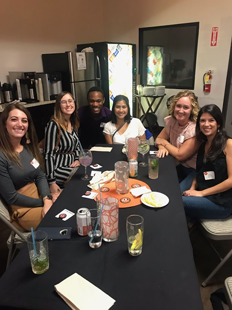 Six alumni smile and pose for a photo at their table