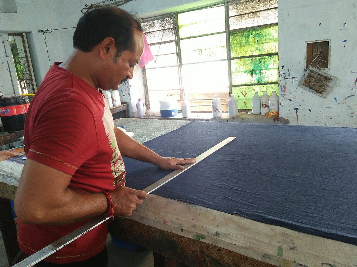 Textiles studio worker measuring and cutting Chelsea's fabric for pillow cases