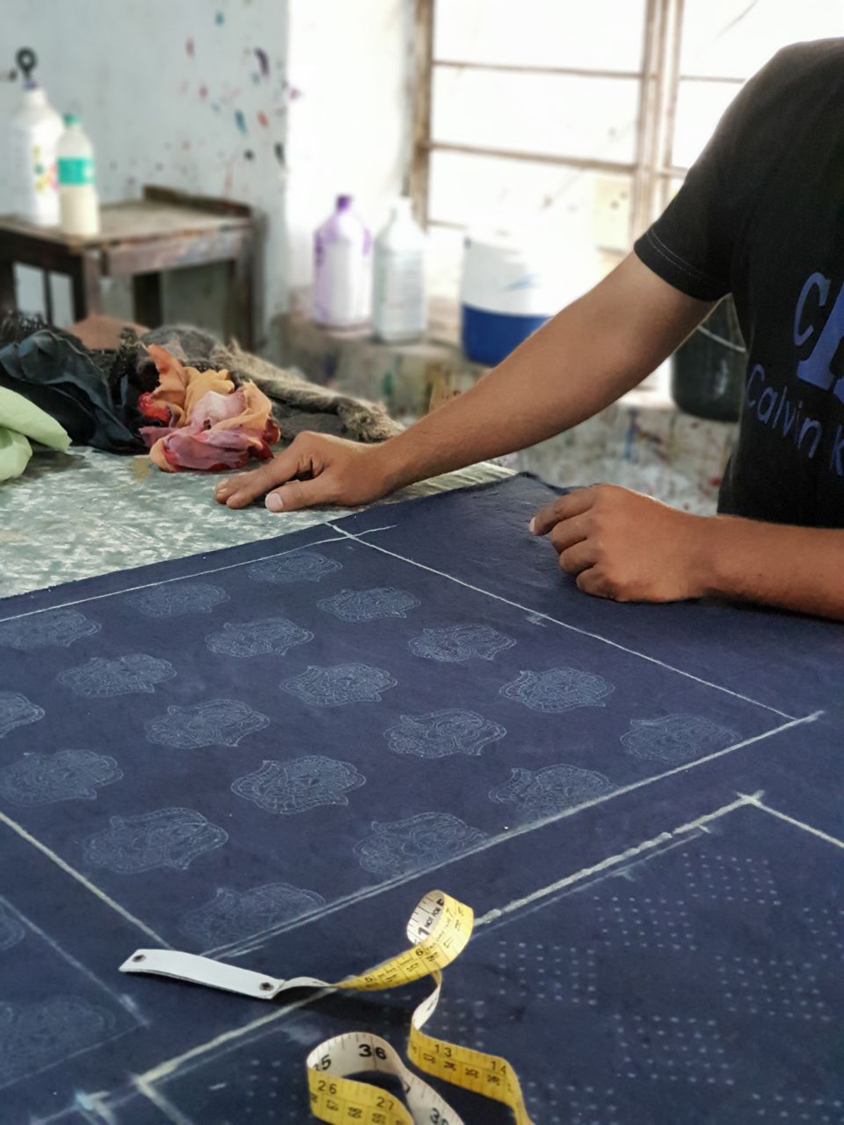 Textiles studio worker completes one side of pillow case square with pattern