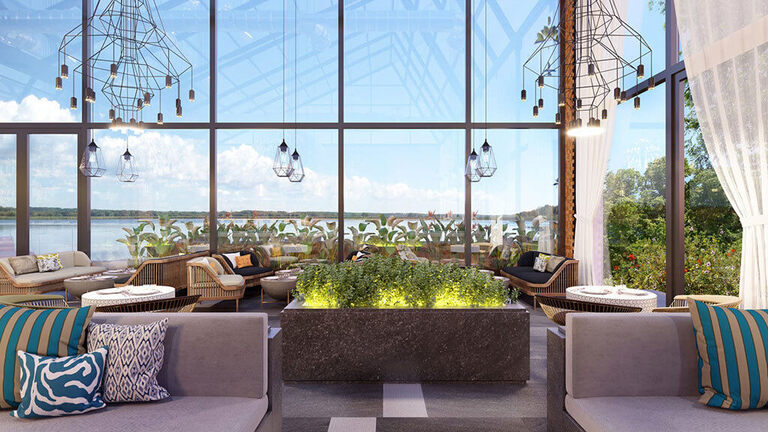 Interior Design Trends 2020 - Anxiety Relieving Space. Image shows a beautiful, tranquil interior space with floor to ceiling windows covering the walls. There is a garden block in the center of a room with plants growing, and surrounding the garden block are various seating options